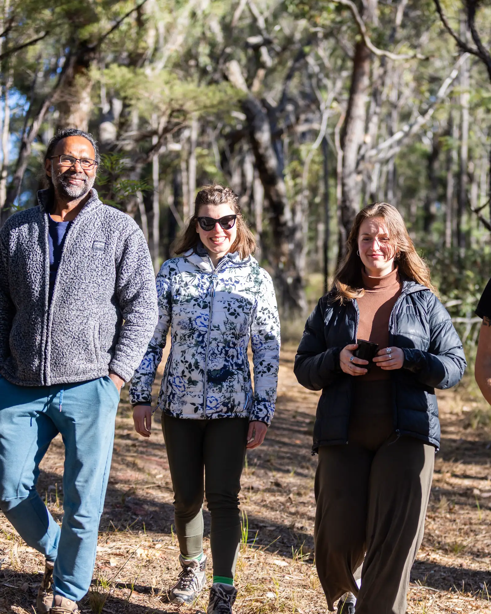 Athil walks with three guests through the bush on a sunny afternoon