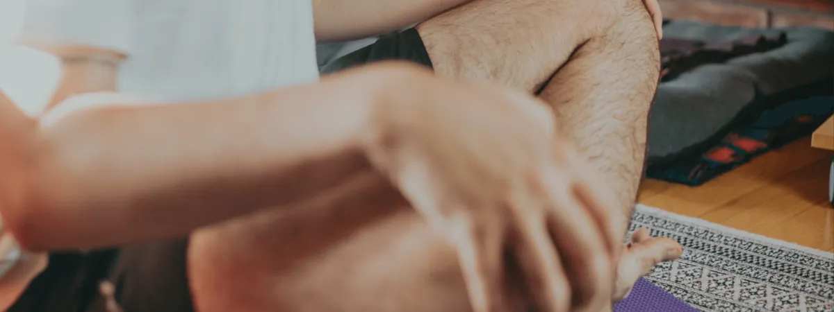 Arms resting on knees beside a yoga mat