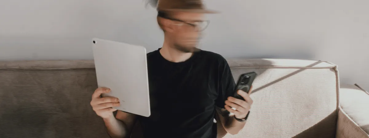 A man holding a tablet in one hand and a phone in the other