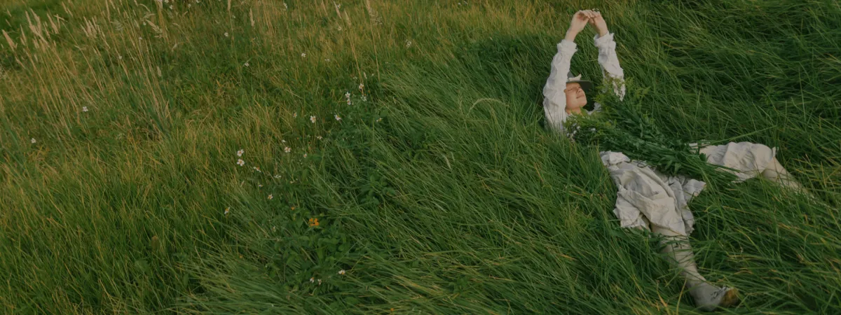 A person lying back in long grass